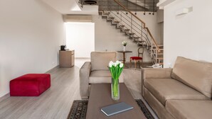 A modern living room with a staircase, a red ottoman, a beige sofa, and a vase with white flowers on a coffee table. - InterContinental Mzaar Lebanon by IHG (Mzaar Kfardebian)