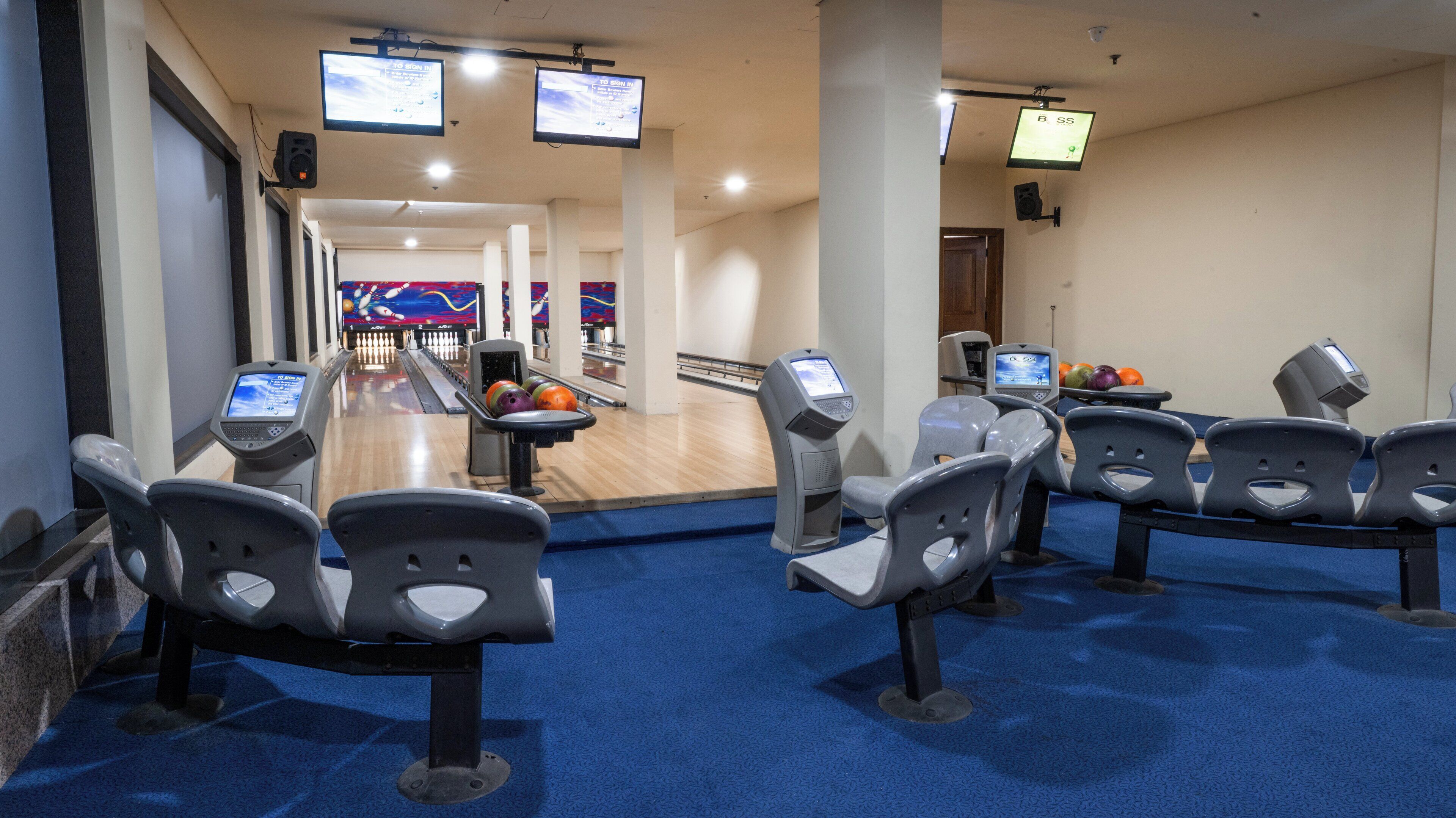 A bowling alley with multiple lanes, bowling balls, and electronic scoreboards.