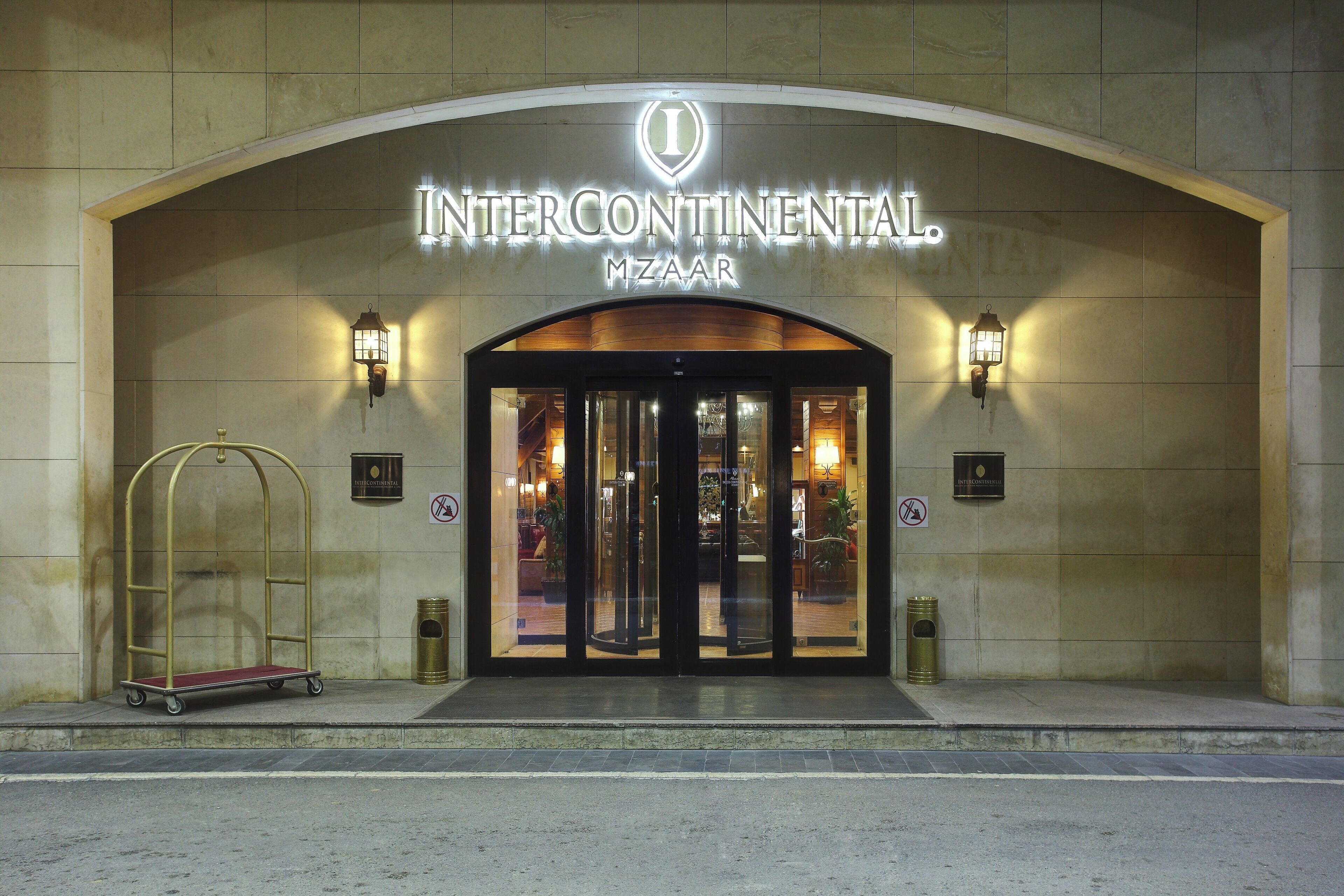 The entrance to Intercontinental Mzara with a glass door and a metal canopy.