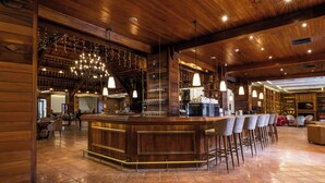 A wooden bar area with a counter and bar stools, a coffee machine, and a television screen. - InterContinental Mzaar Lebanon by IHG (Mzaar Kfardebian)