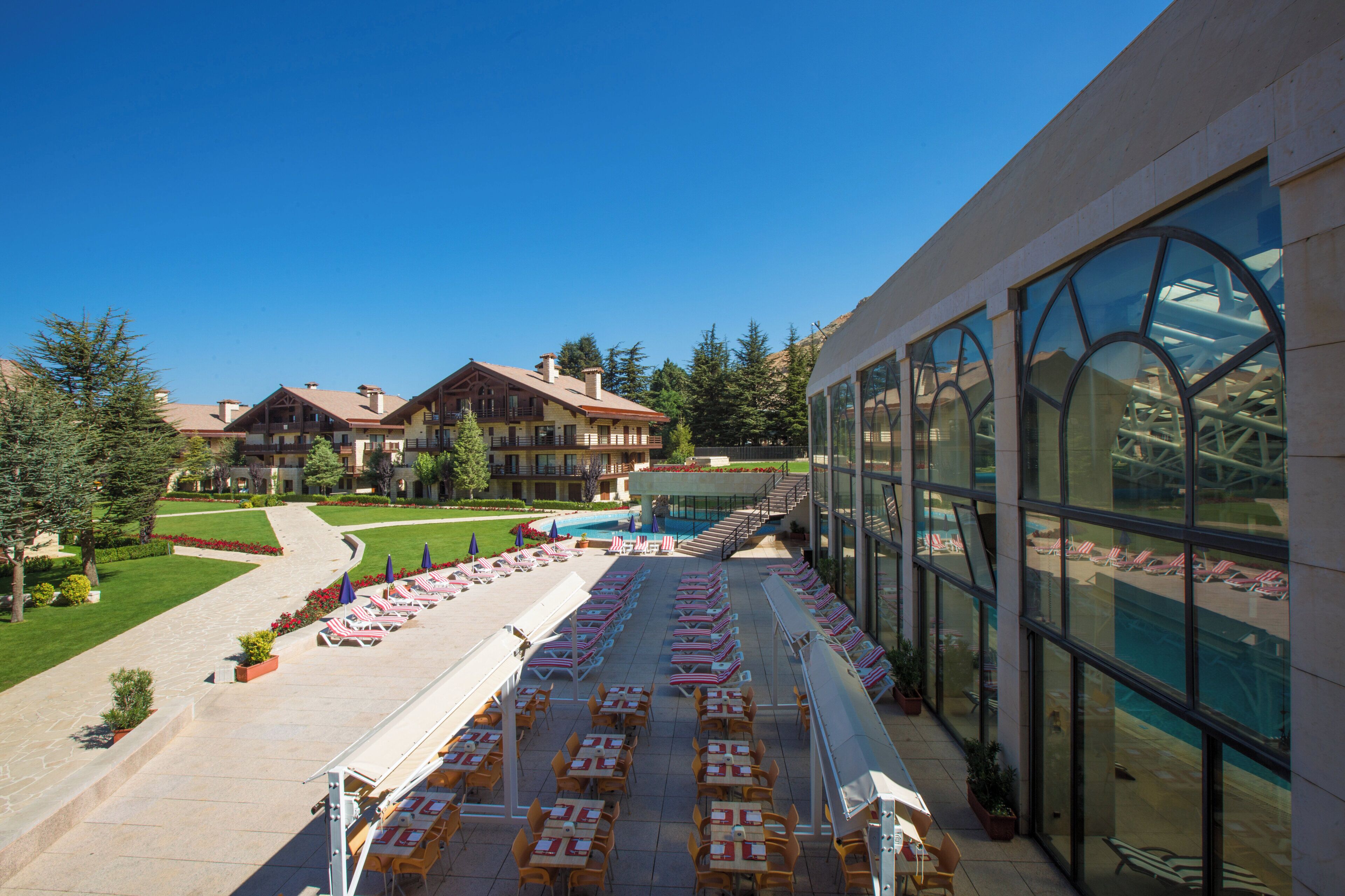 A hotel with a pool area, outdoor seating, and a view of the surrounding landscape.