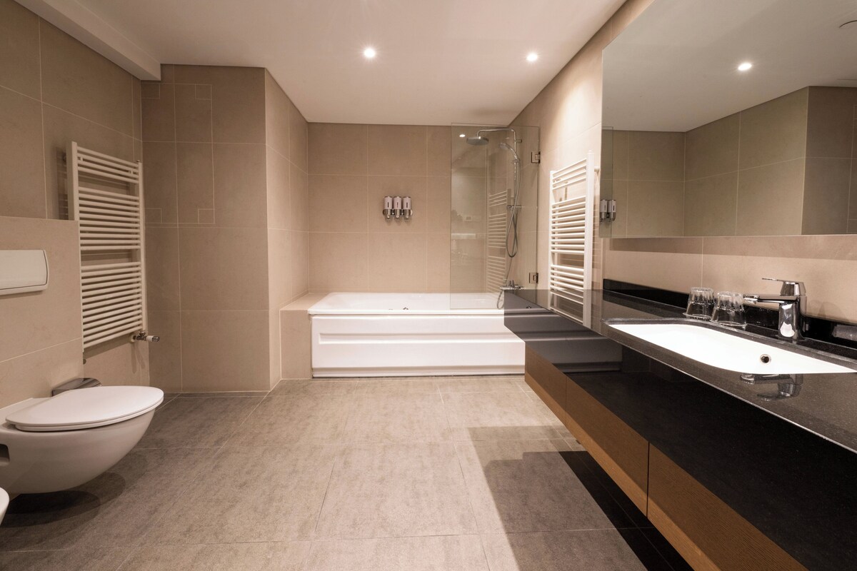 A modern bathroom with a bathtub, toilet, and sink.