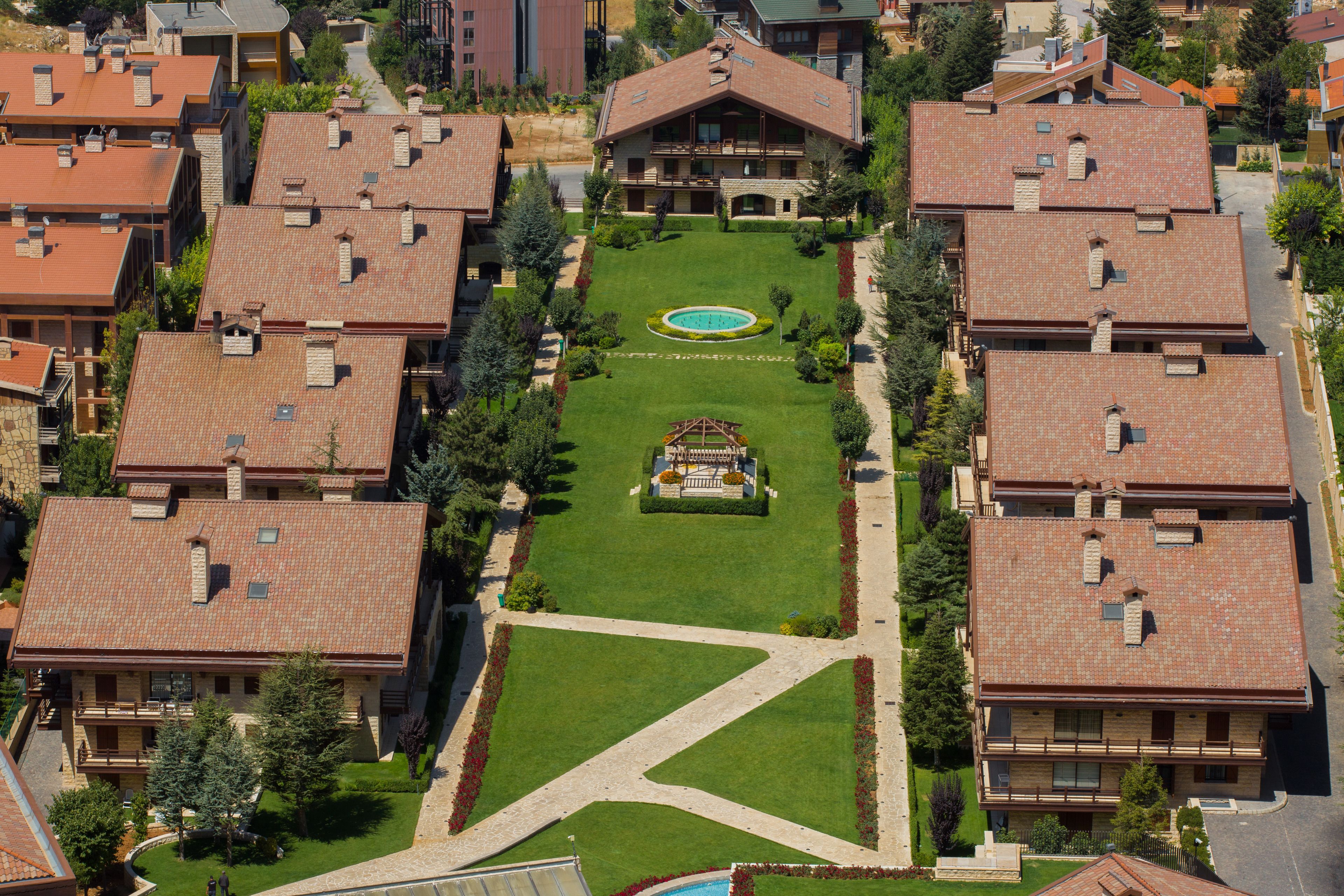 Vista aérea de una zona residencial con varias casas de dos pisos, cada una con techo de tejas y un patio central.