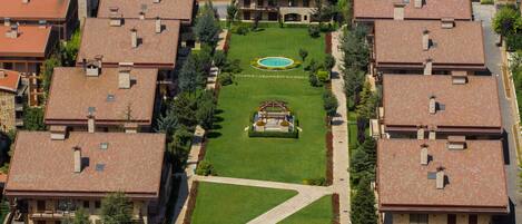 An aerial view of a residential area with multiple two-story houses, each with a tiled roof and a central courtyard.