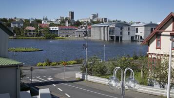 A view of a waterfront street with buildings, a body of water, and a white fence.