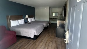 A hotel room with a double bed, a small desk, a mirror, and a door marked with the number 109. - Key West Inn - Clanton (Clanton)