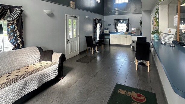 A spacious hotel room with a large bed, a desk, and a kitchenette. There are ceiling fans, a window, and a door. - Key West Inn - Clanton (Clanton)