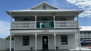 A two-story building with a green sign reading "Key West Inn" and a "Lobby" sign above the entrance. - Key West Inn - Clanton (Clanton)