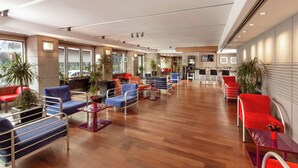 Un hall amplio con asientos modernos, una zona de recepción y grandes ventanales con vistas.
