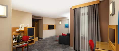 Une chambre d’hôtel équipée d’un bureau, d’une chaise, d’un canapé et d’une télévision.
