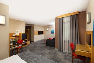 Habitación de hotel con escritorio, silla, sofá y televisión.