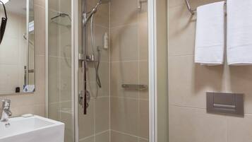 A modern bathroom with a glass-enclosed shower, a white sink, and a toilet.