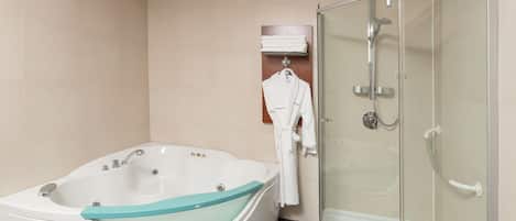 Un baño moderno con una bañera independiente, una ducha con cerramiento de vidrio y un perchero con bata blanca.