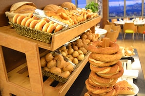 En buffet med forskellige bagværk, herunder brød og kager, præsenteret på træfade.