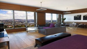 Een moderne woonkamer met een groot raam, een bank, een salontafel en een eethoek.