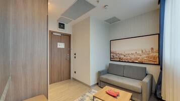 Ein modernes Hotelzimmer mit einer Couch, einem Couchtisch und einem großen Stadtbild an der Wand.