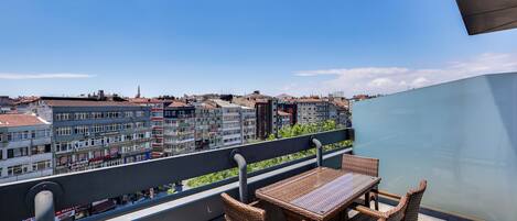 A balcony with wicker furniture and a view of a cityscape.