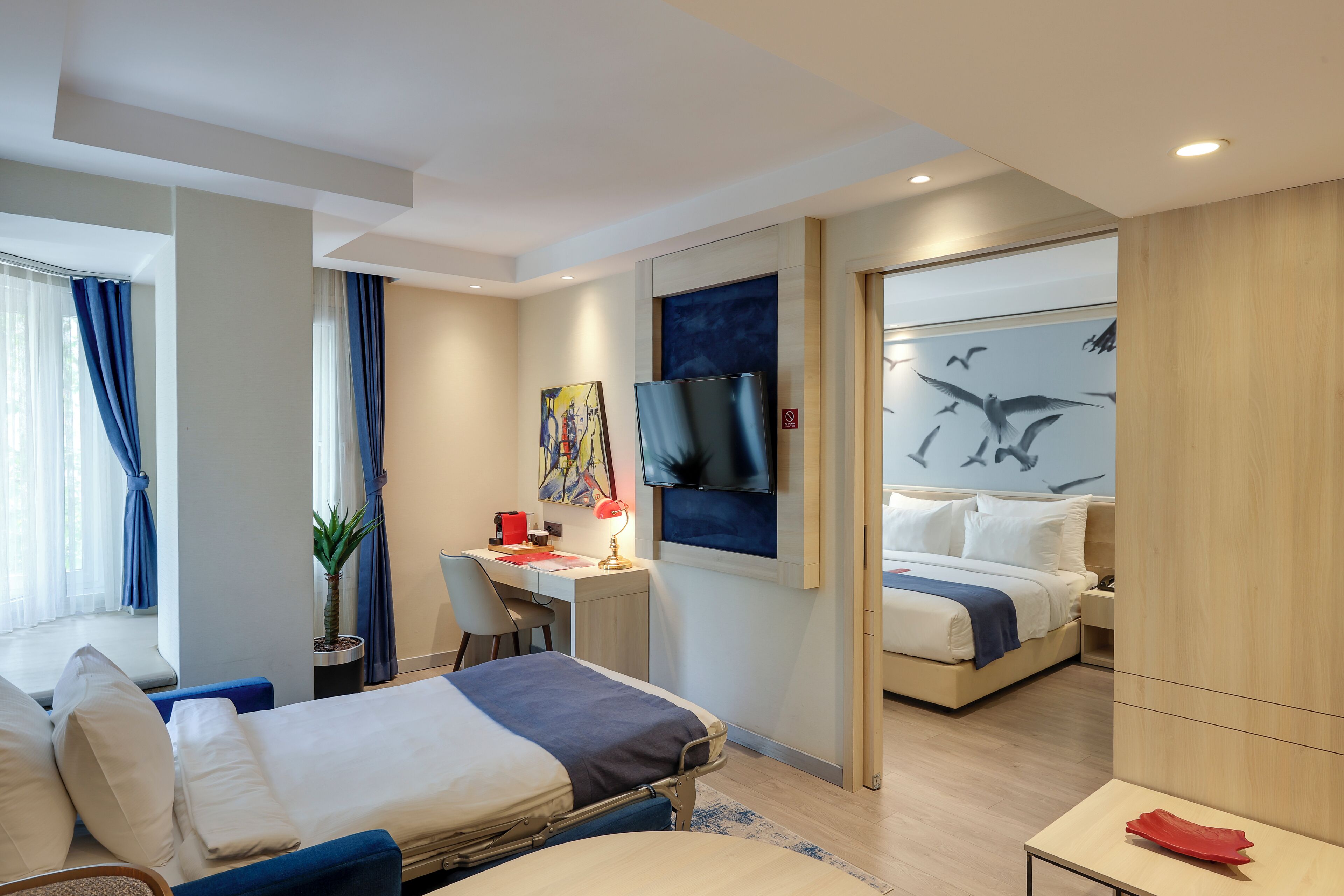 Een moderne hotelkamer met een bed, bureau en zithoek.