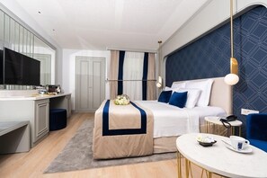 Una habitación de hotel con cama, mesita de noche, escritorio y televisor.