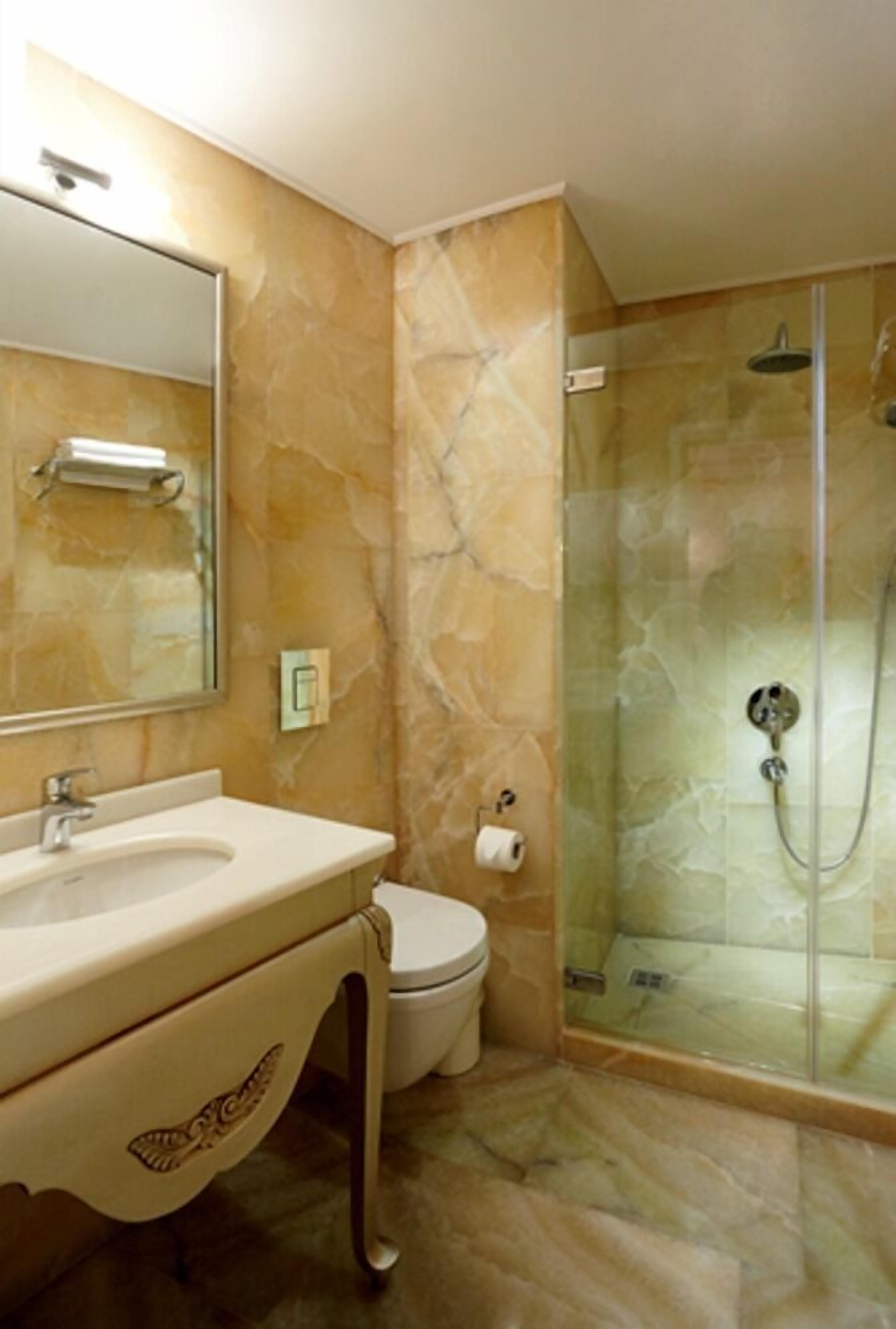 Ein Badezimmer mit Marmorwaschbecken, Toilette und einer Duschkabine.