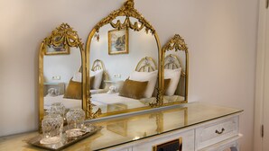 Une chambre à coucher avec un grand miroir, une table de chevet sur laquelle se trouve une assiette avec des verres, et un lit avec des oreillers.