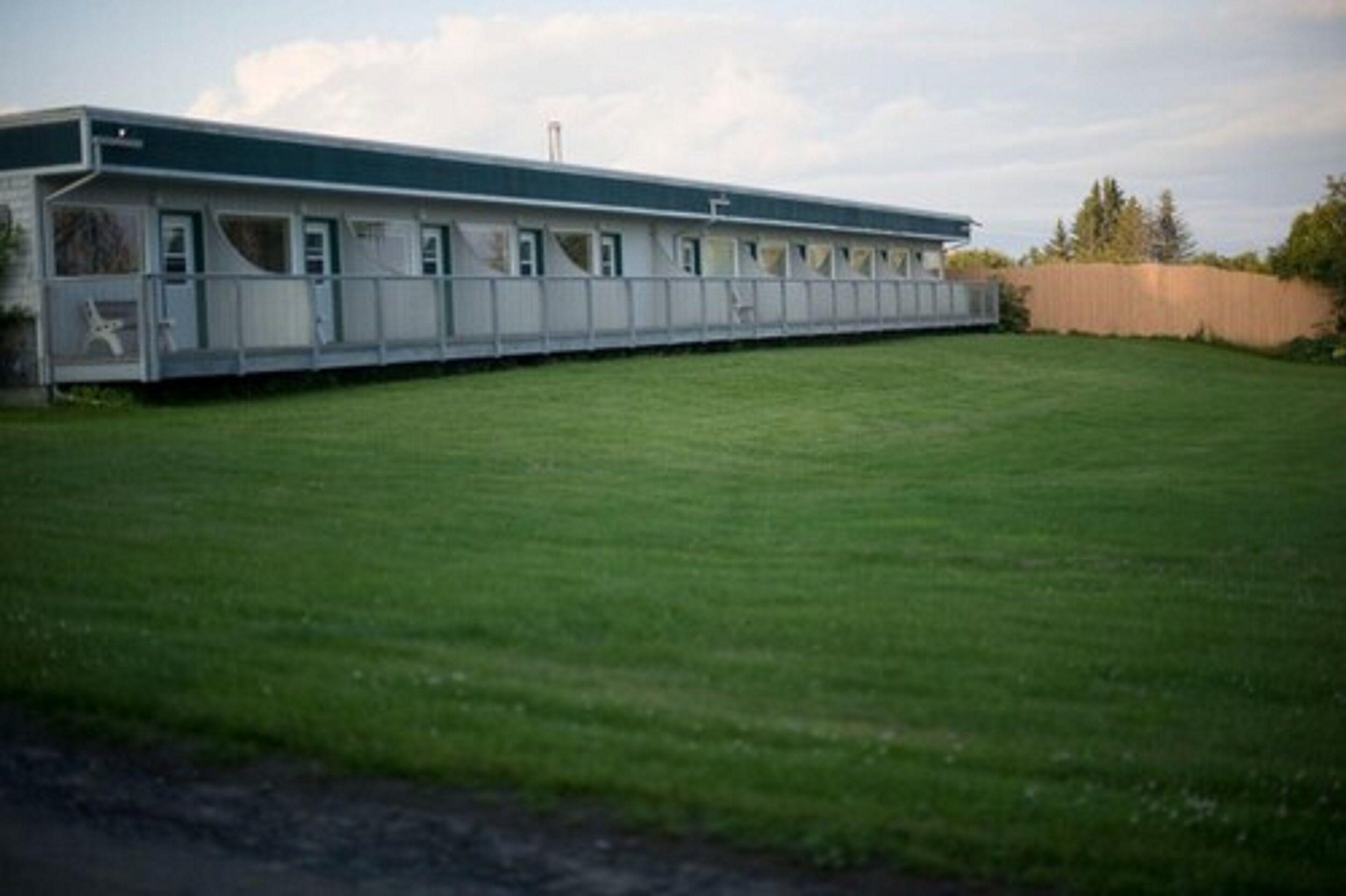 A long, single-story building with a flat roof and a series of windows along the side.