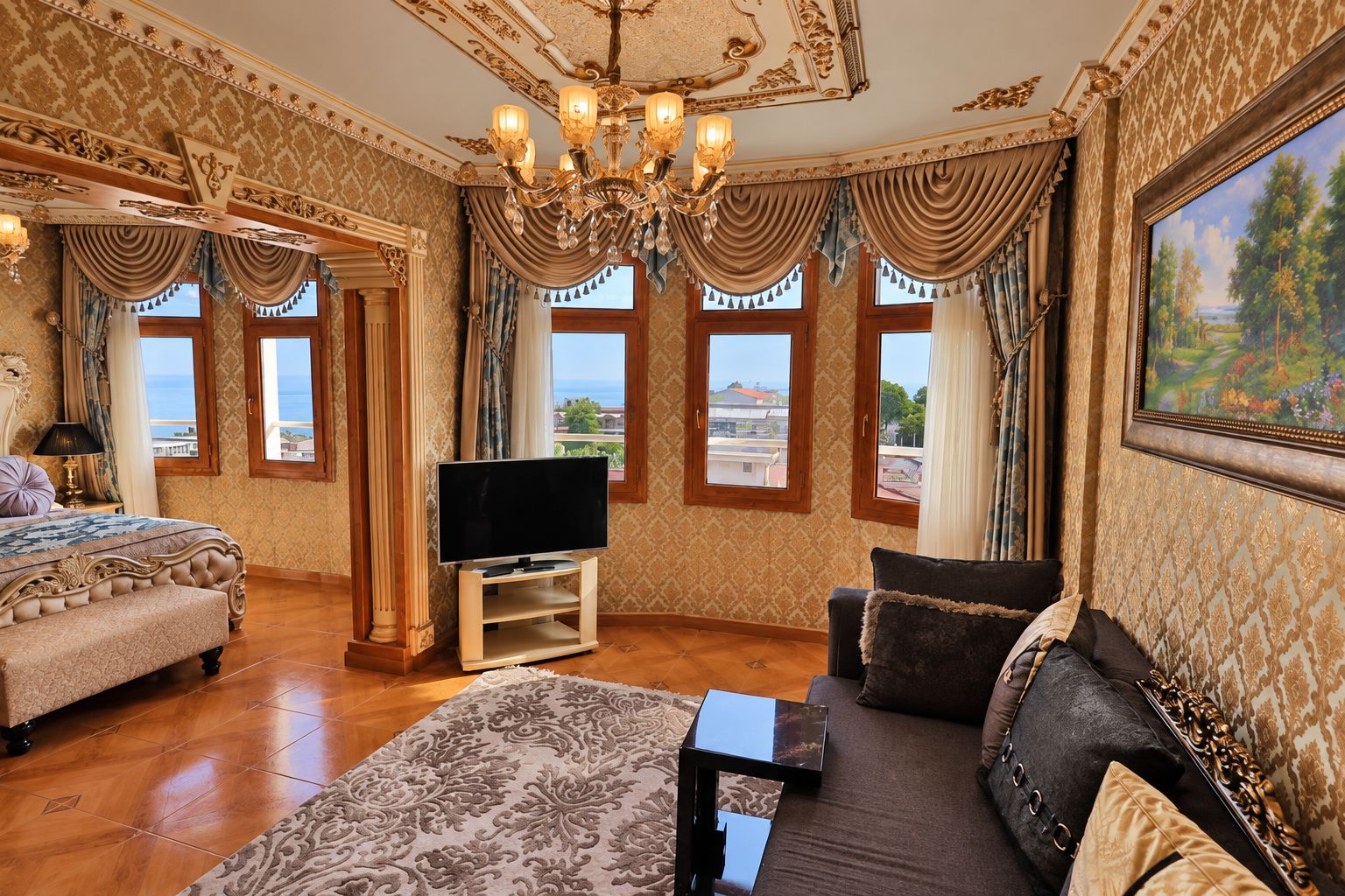 A luxurious room with a large bed, a sofa, a television, and a painting.