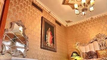 Una habitación lujosa con decoraciones ornamentales en el techo, un espejo grande y una cama cómoda.