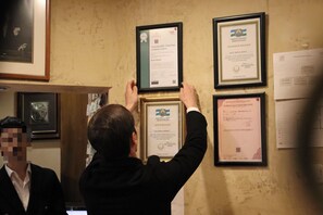 A person hanging framed documents on a wall. - Blue House Hotel (Istanbul)