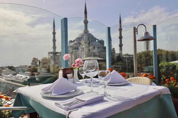 A table set for two with a view of a mosque and a body of water in the background. - Blue House Hotel (Istanbul)