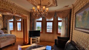 A luxurious room with a large bed, a sofa, a TV, and a painting on the wall. - Blue House Hotel (Istanbul)