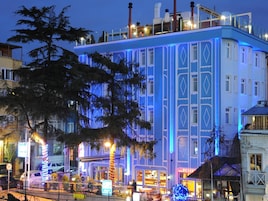 Ein mehrstöckiges Gebäude mit auffälliger blau-weißer Fassade, großen Fenstern und einer Dachterrasse.