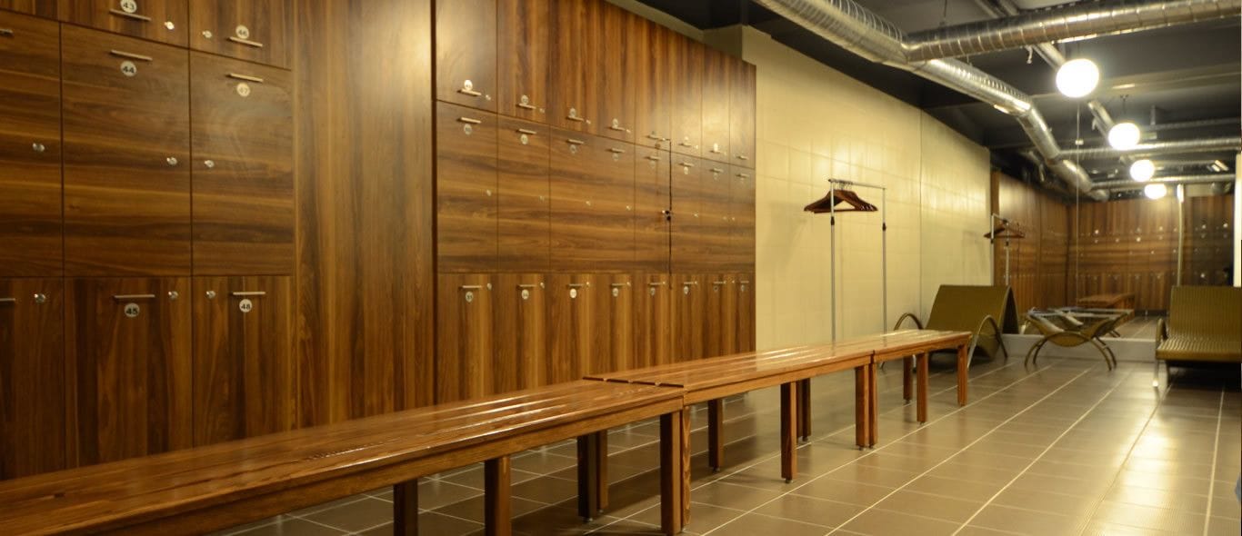 Un vestiaire avec des casiers en bois, un banc et un espace pour se changer.