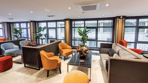 Un vestíbulo moderno con mostrador de recepción, zona de estar y ventanas amplias.