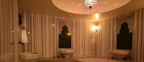 A bathroom with striped walls, two sinks, a mirror, and a decorative ceiling light.