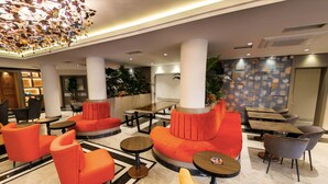 Un hall con asientos rojos y amarillos, techo decorativo y pared con diseño.