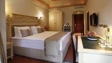Una habitación de hotel con una cama grande, un armario, un escritorio con un frutero y un espejo en la pared.