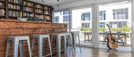 A bar area with a wooden counter, metal stools, and a guitar.