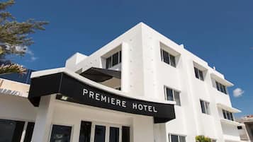 Un hôtel moderne, reconnaissable à son enseigne bien visible où l’on peut lire « PREMIERE HOTEL ».