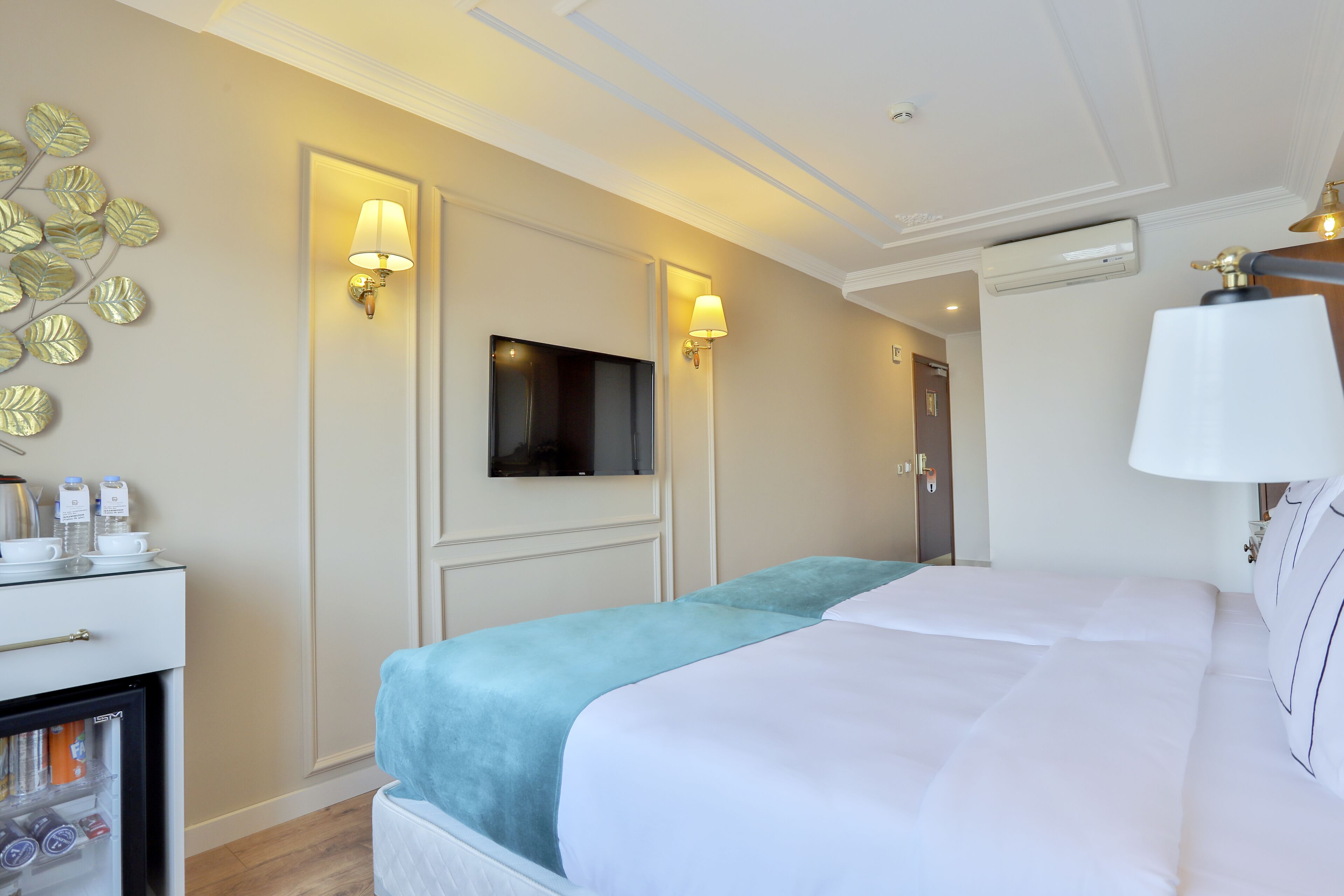 Habitación de hotel con cama, televisor montado en la pared y un minibar.