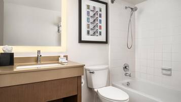 Un baño con lavamanos, inodoro, bañera y un cuadro en la pared.