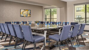 A conference room with a long table, chairs, water bottles, and a large window.