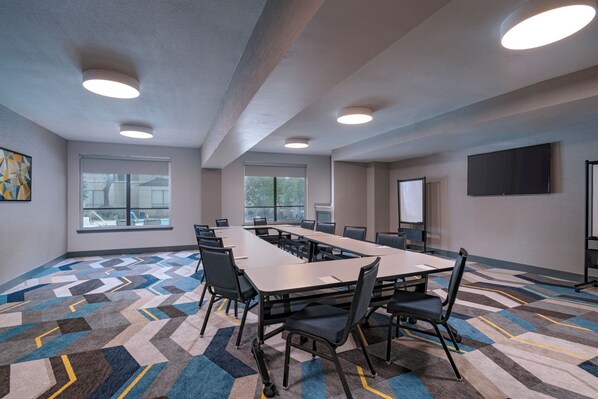 A conference room with a long table, chairs, and a projector screen.