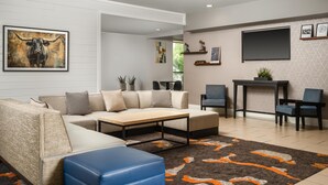 A modern living room with a sectional sofa, a coffee table, and a TV. There are two chairs, a small table, and a rug.