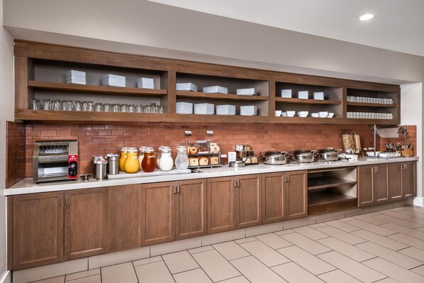 A kitchen with wooden cabinets, a brick backsplash, and various kitchen appliances and utensils.