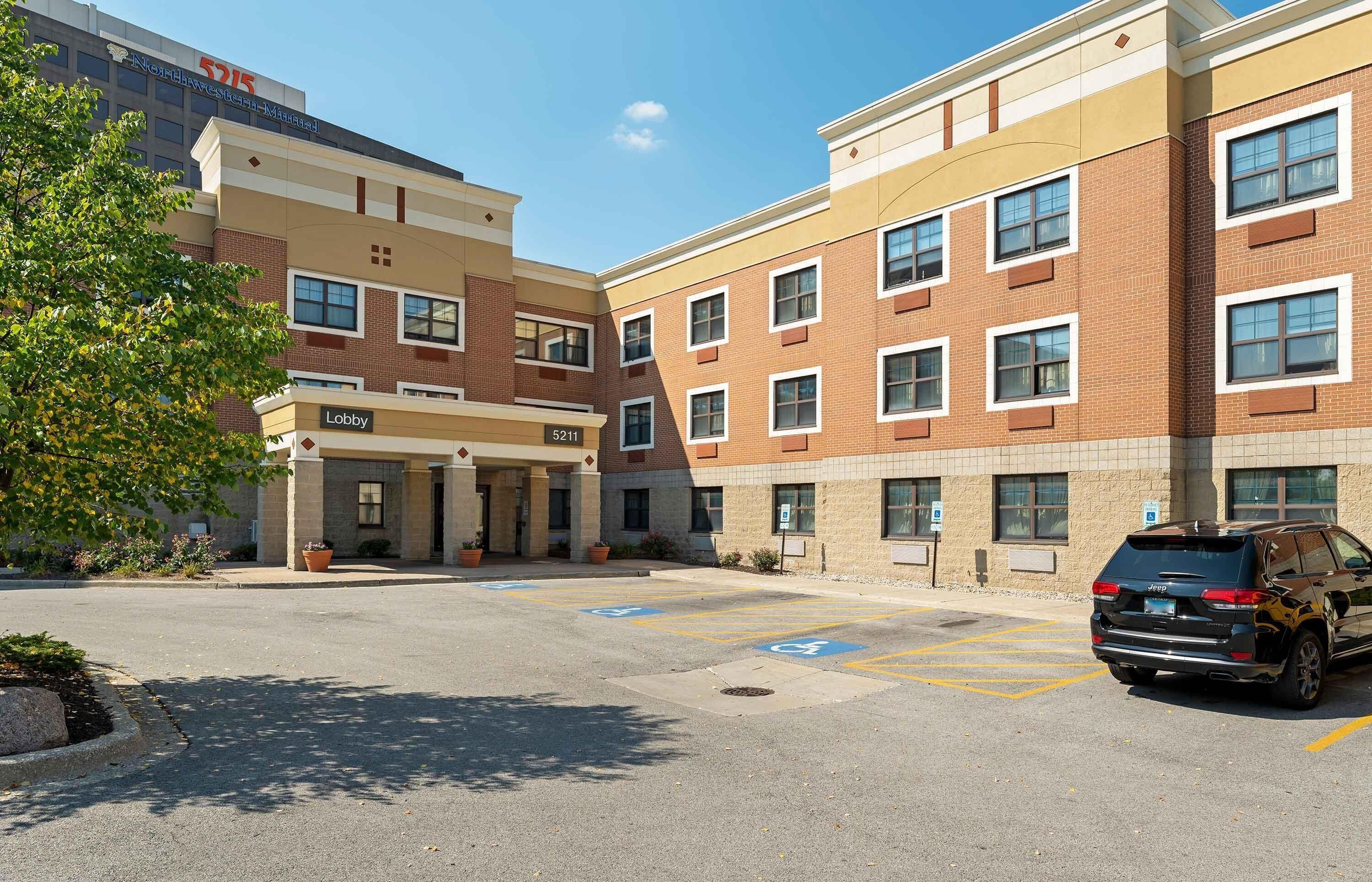 A multi-story hotel with a lobby, parking area, and a Jeep SUV parked in the lot.