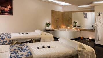 Experience relaxation in this serene spa room with a bathtub, massage tables, and calming ambiance.