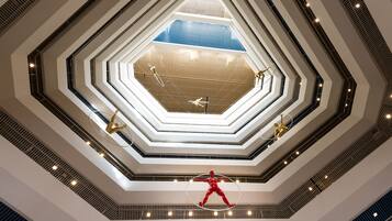 A multi-level atrium with a central skylight and a red sculpture.