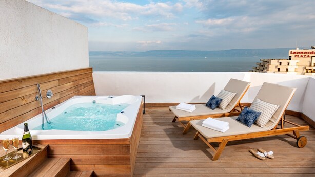 Une terrasse sur le toit avec un jacuzzi, des chaises longues et une vue sur la mer.