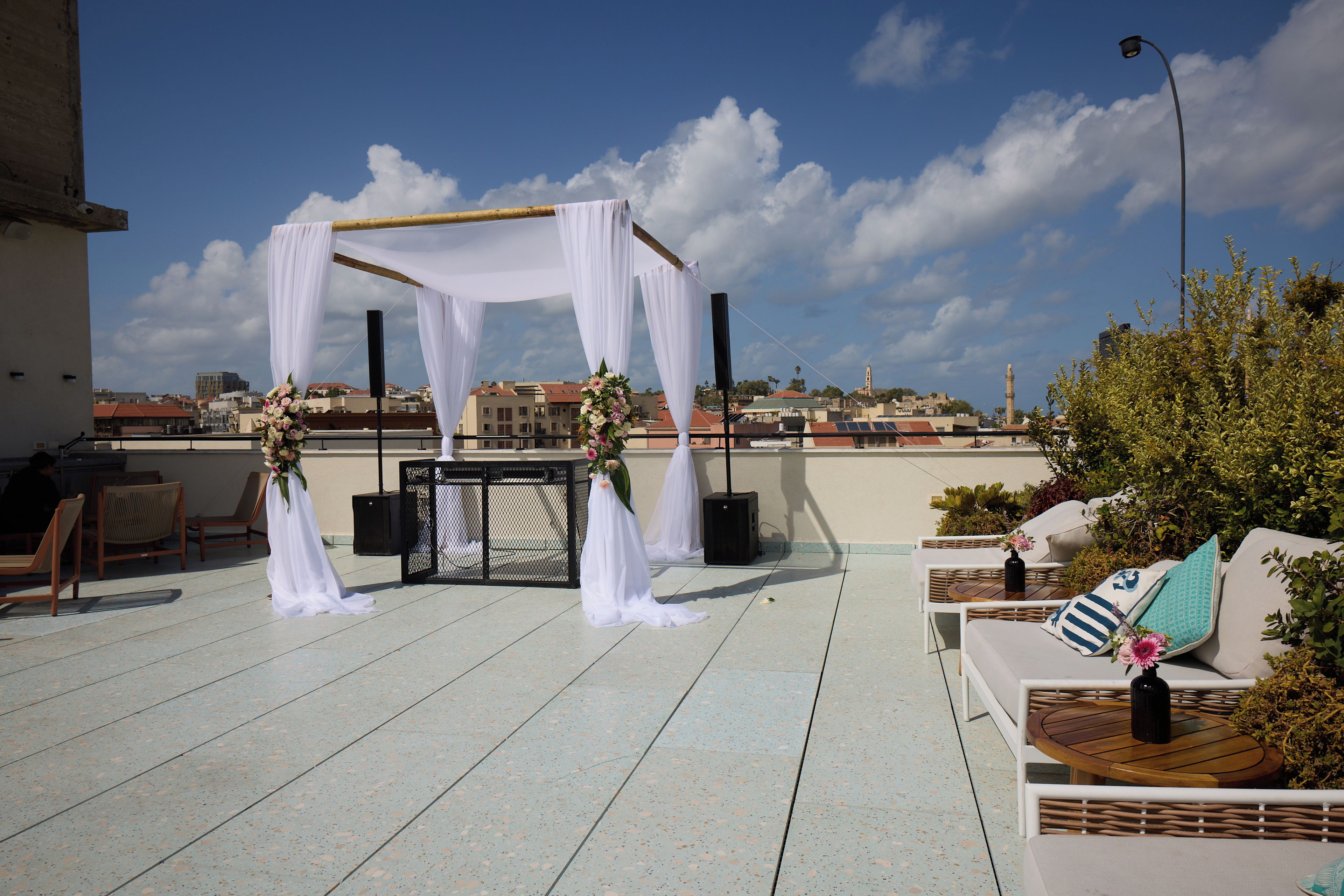 A rooftop terrace with a white canopy, seating area, and a view of the cityscape.
